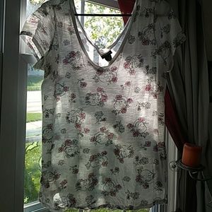 White v neck t-shirt with skulls and pink flowers.
